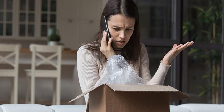 This shows a woman on a phone call, appearing frustrated as she looks into an open package.