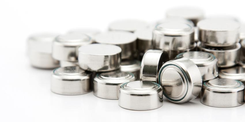 A stack of small, silver button batteries, commonly used in electronic devices. The background is plain and white, putting full focus on the batteries.